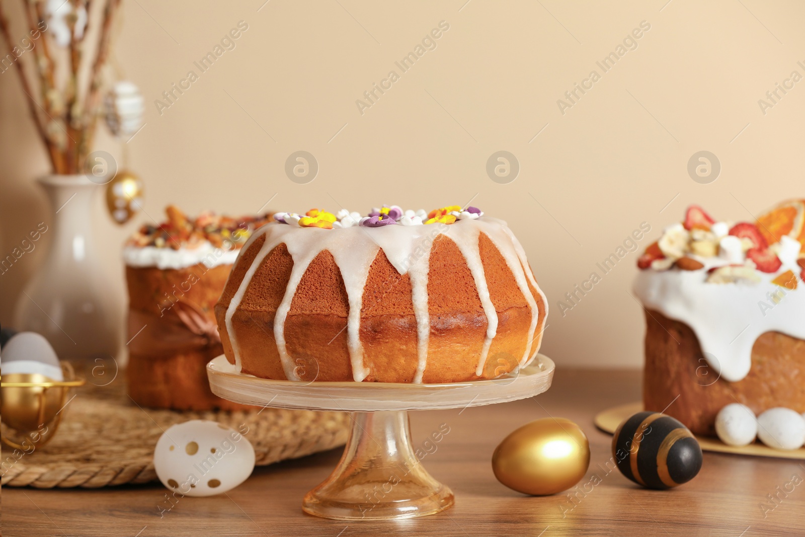 Photo of Delicious Easter cakes decorated with sprinkles near painted eggs on wooden table