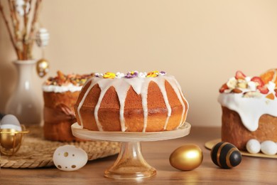 Photo of Delicious Easter cakes decorated with sprinkles near painted eggs on wooden table