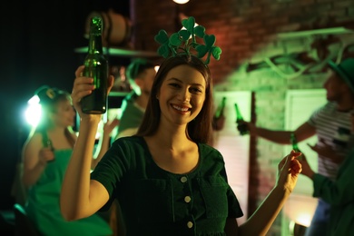 Woman with beer celebrating St Patrick's day in pub