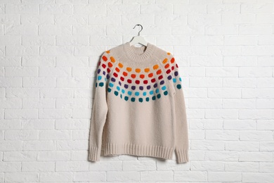 Hanger with stylish sweater on brick wall