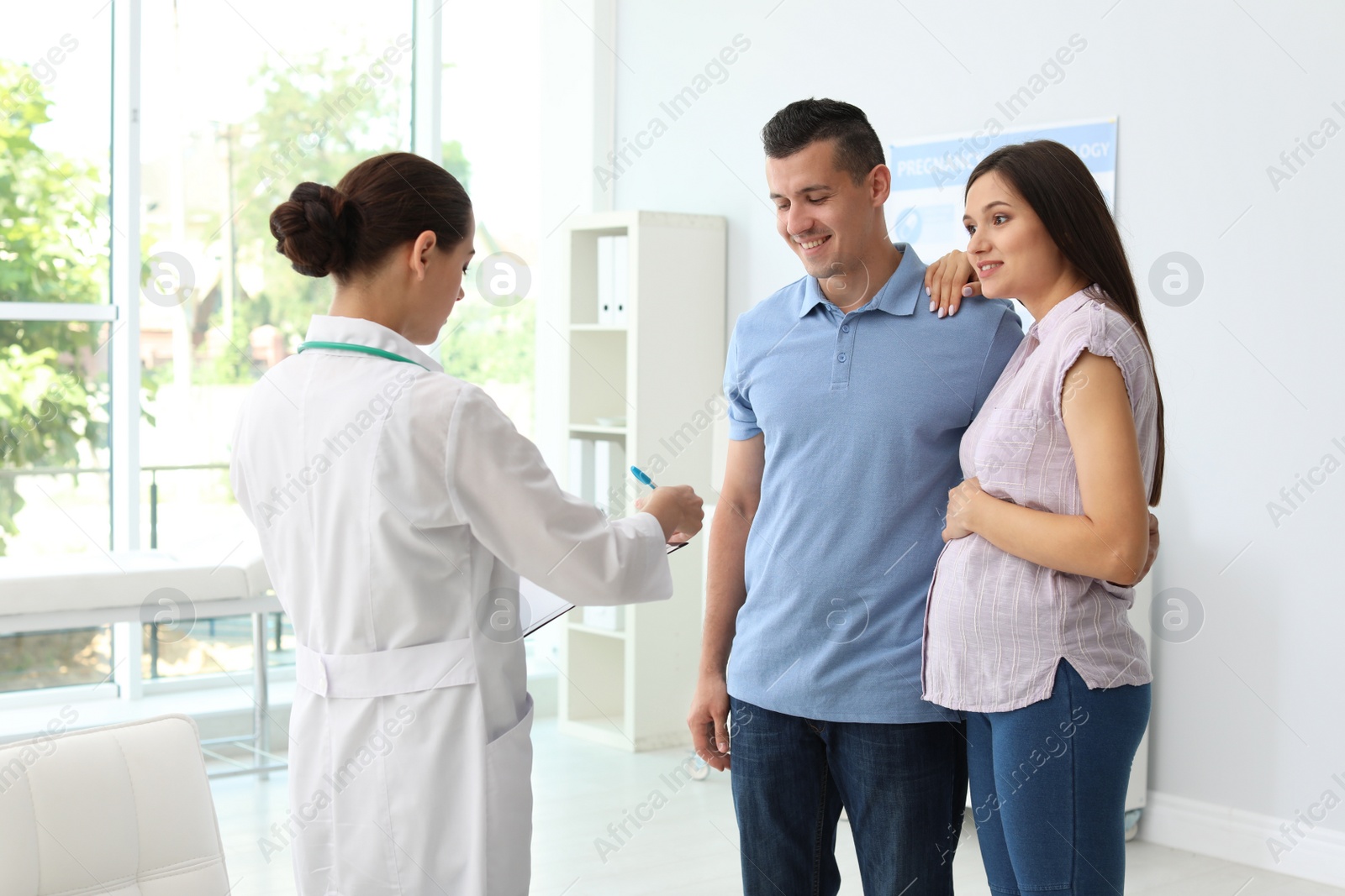 Photo of Doctor talking to young family in hospital. Patient consultation