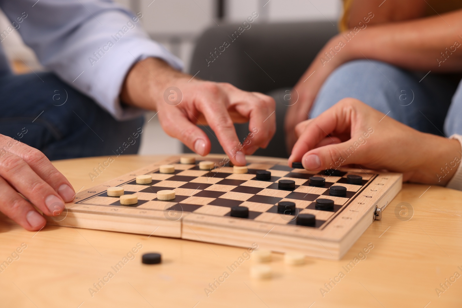 Photo of People playing checkers at wooden table indoors, closeup