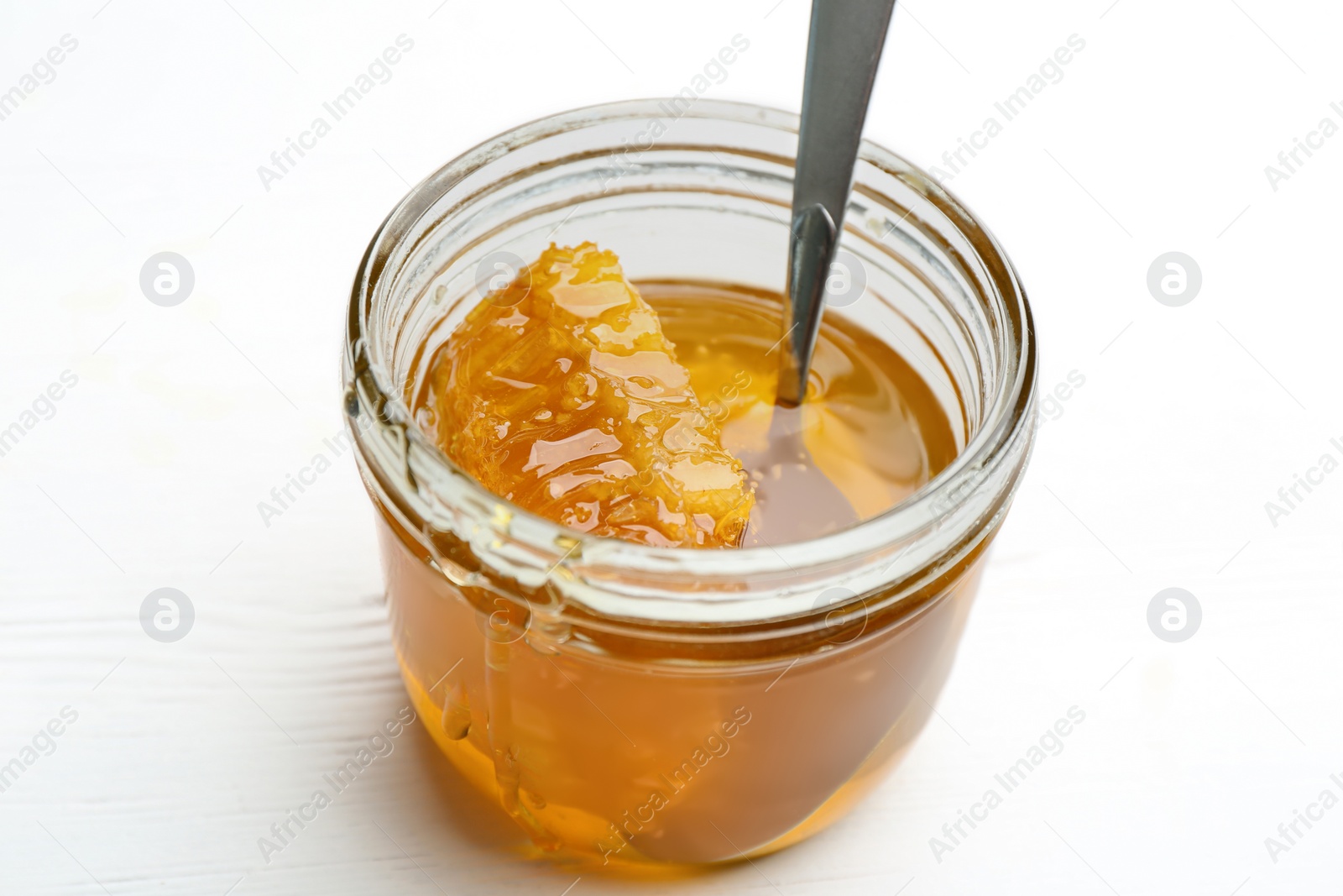 Photo of Tasty honey with comb on white wooden table, closeup