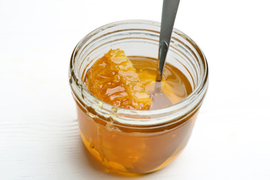 Tasty honey with comb on white wooden table, closeup