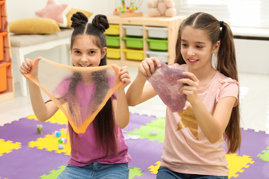 Photo of Happy girls playing with slime in room