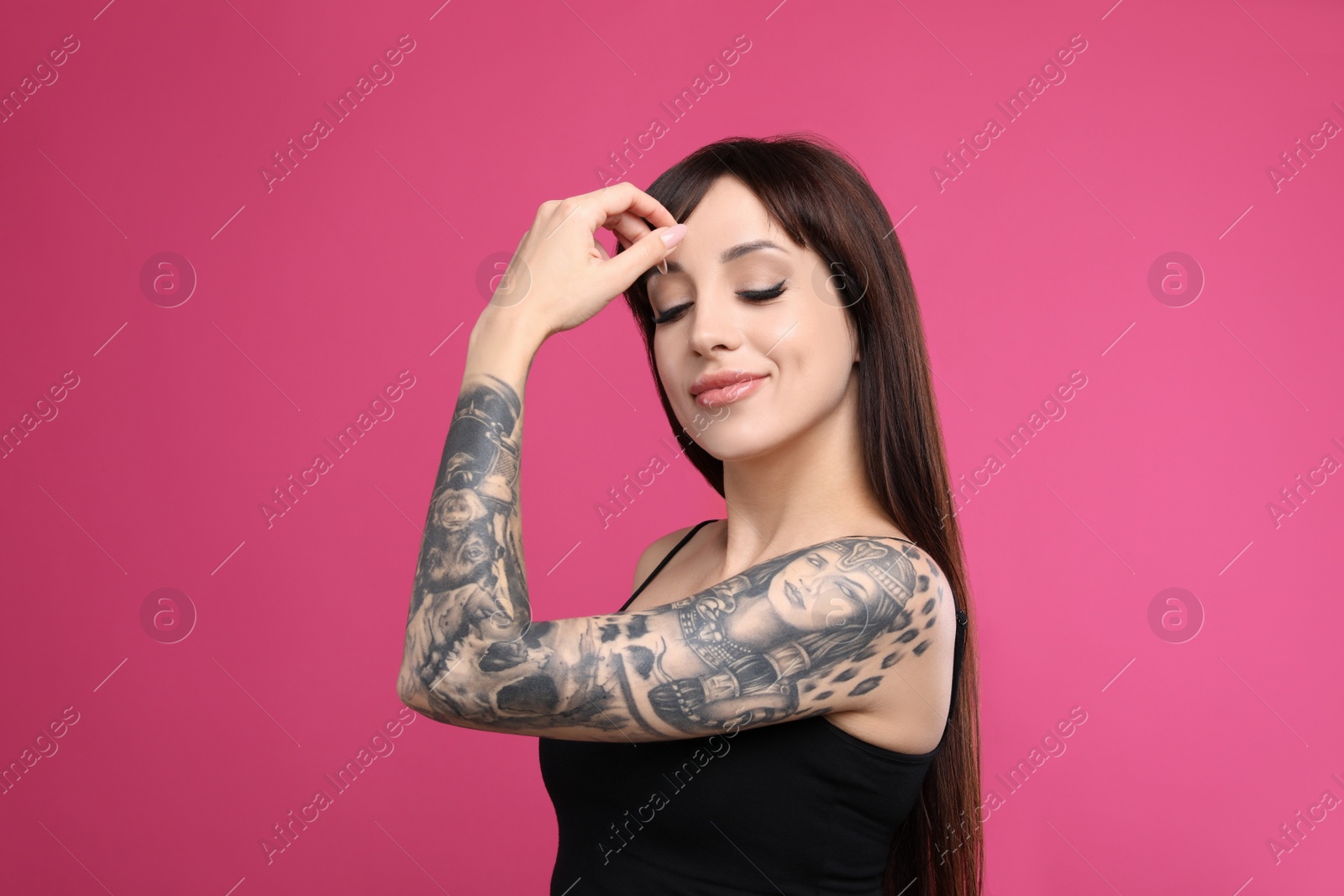 Photo of Woman with tattoos on arm against pink background