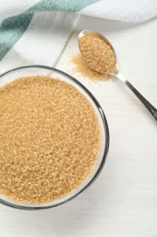 Photo of Brown sugar in bowl and spoon on white wooden table, flat lay