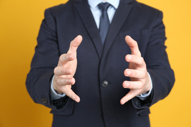 Businessman holding something against orange background, focus on hands