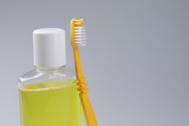 Photo of Fresh mouthwash in bottle and toothbrush on grey background, closeup. Space for text