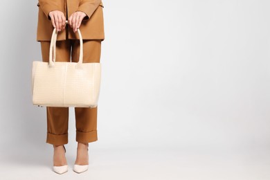 Young woman with stylish bag on white background, closeup