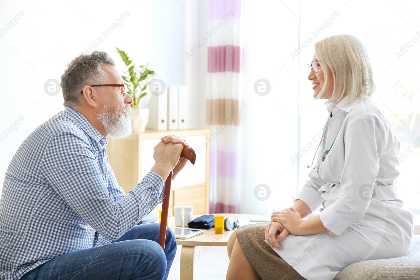 Photo of Mature doctor consulting patient at home