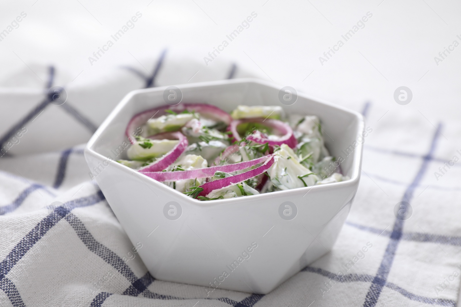 Photo of Delicious fresh cucumber onion salad with dressing in bowl on table