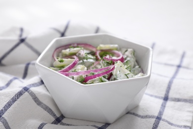 Delicious fresh cucumber onion salad with dressing in bowl on table