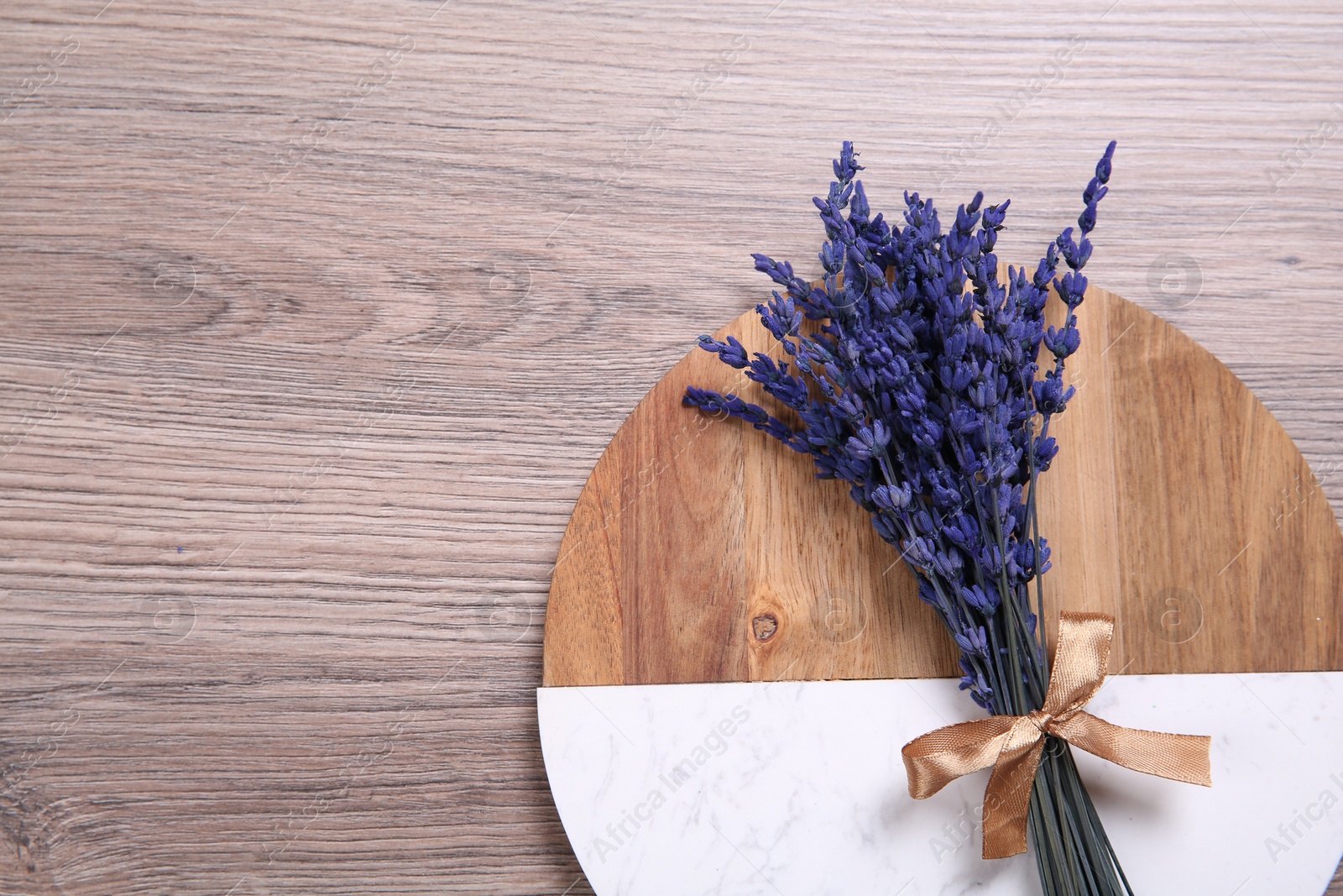 Photo of Bouquet of beautiful preserved lavender flowers and board on wooden table, top view. Space for text