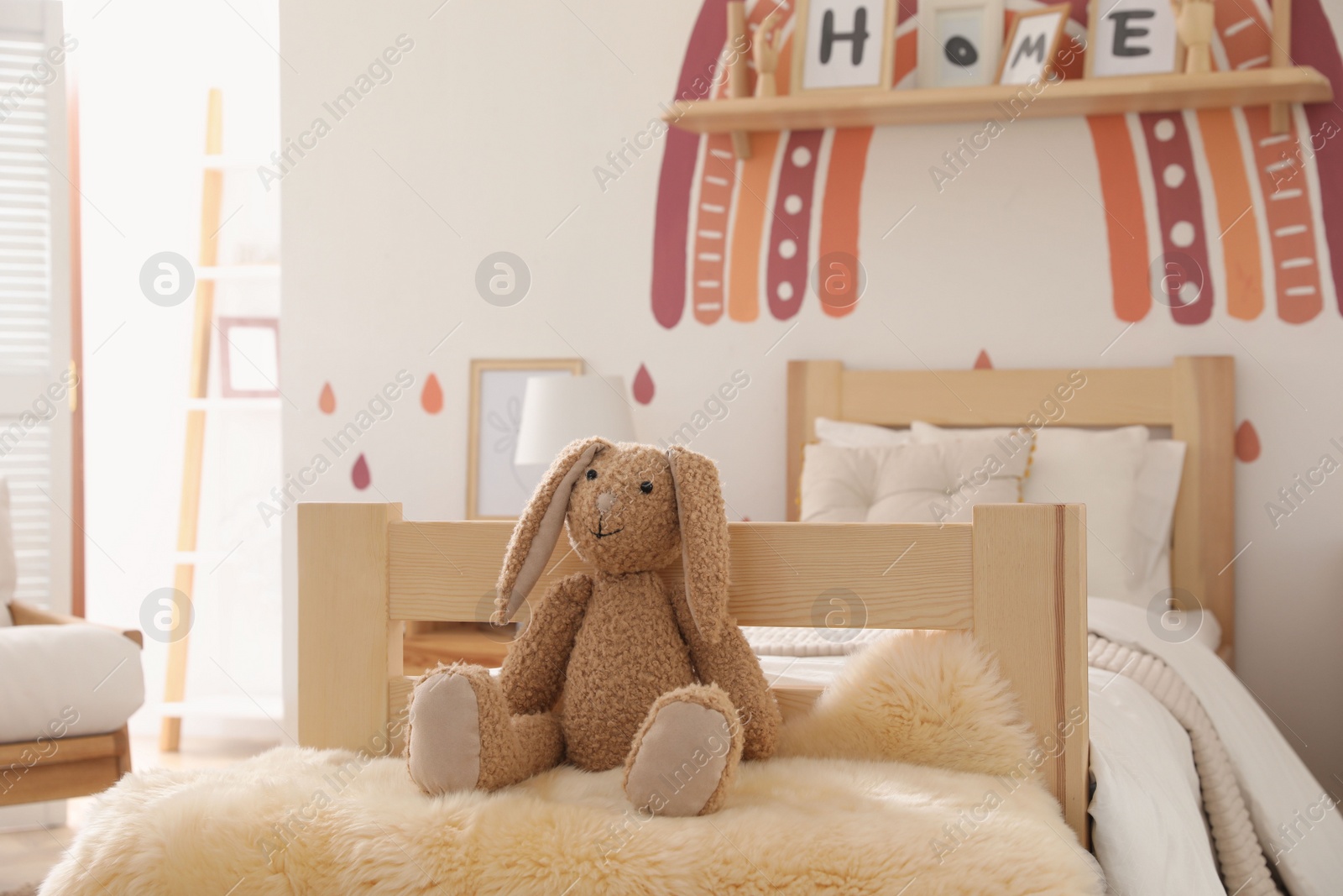 Photo of Toy bunny on faux fur in modern girl's bedroom. Interior design