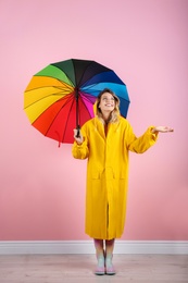 Woman with rainbow umbrella near color wall