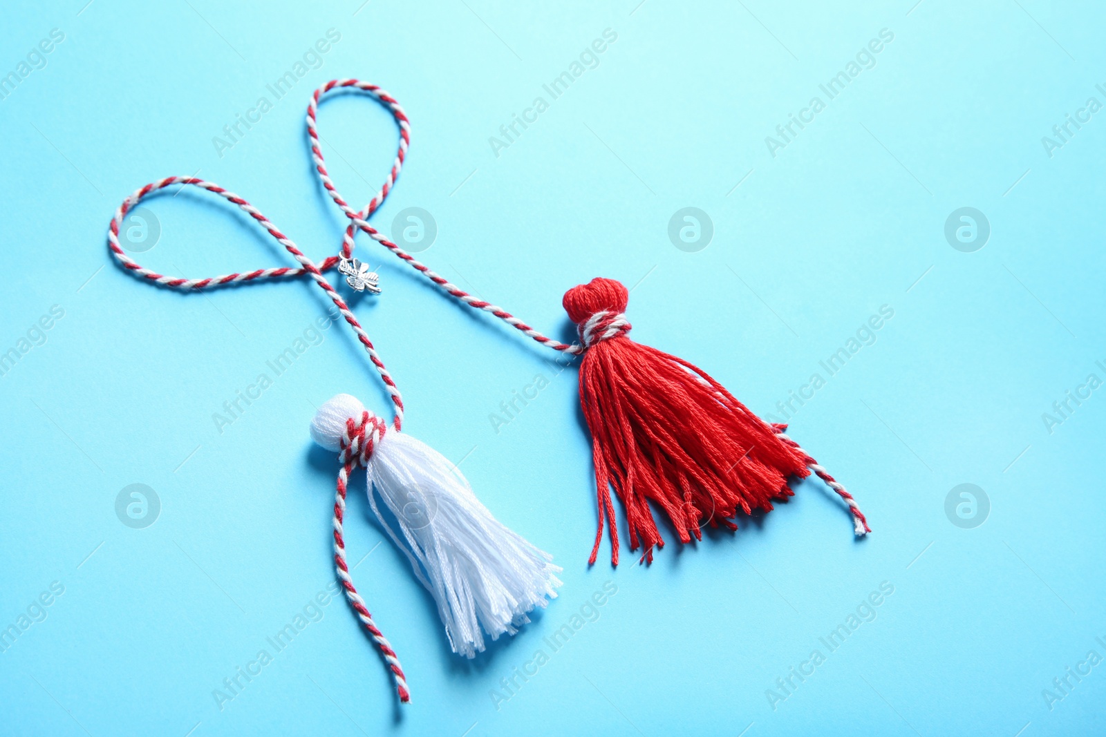 Photo of Traditional martisor on light blue background. Beginning of spring celebration