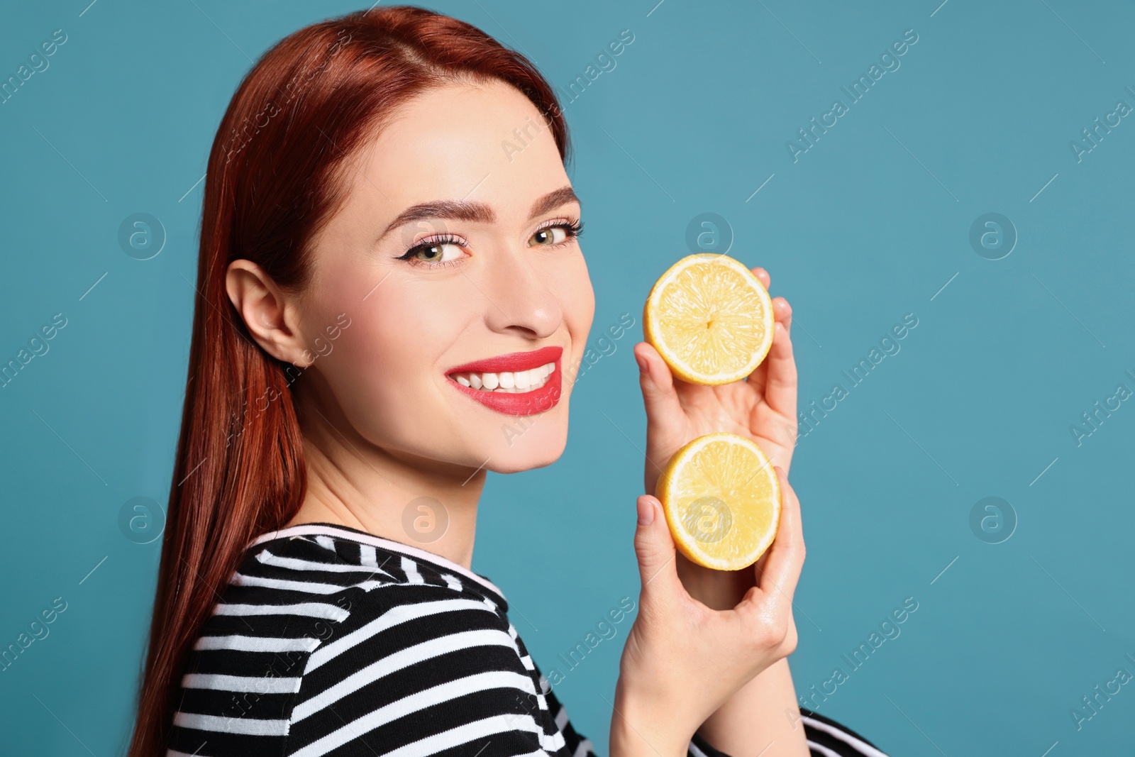 Photo of Happy woman with red dyed hair and lemons on light blue background