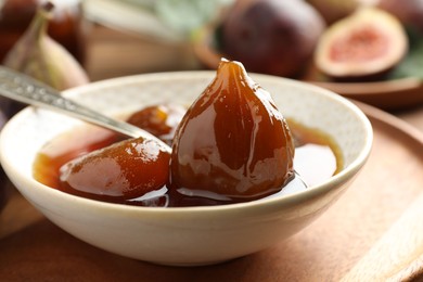 Bowl of tasty sweet fig jam on wooden table, closeup