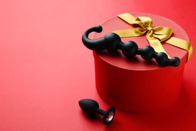 Photo of Gift box with sex toys on red background. Space for text