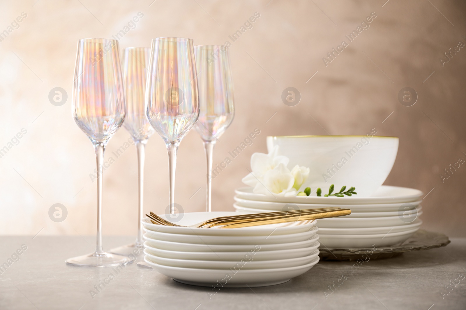 Photo of Set of glasses and dishes with flowers on light grey table