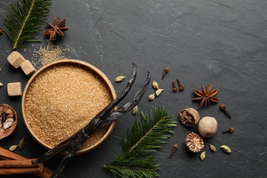 Photo of Different aromatic spices and fir branches on dark textured table, flat lay. Space for text