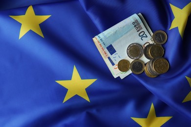 Photo of Coins and banknotes on European Union flag, flat lay. Space for text