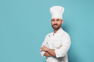 Photo of Smiling mature chef on light blue background, space for text