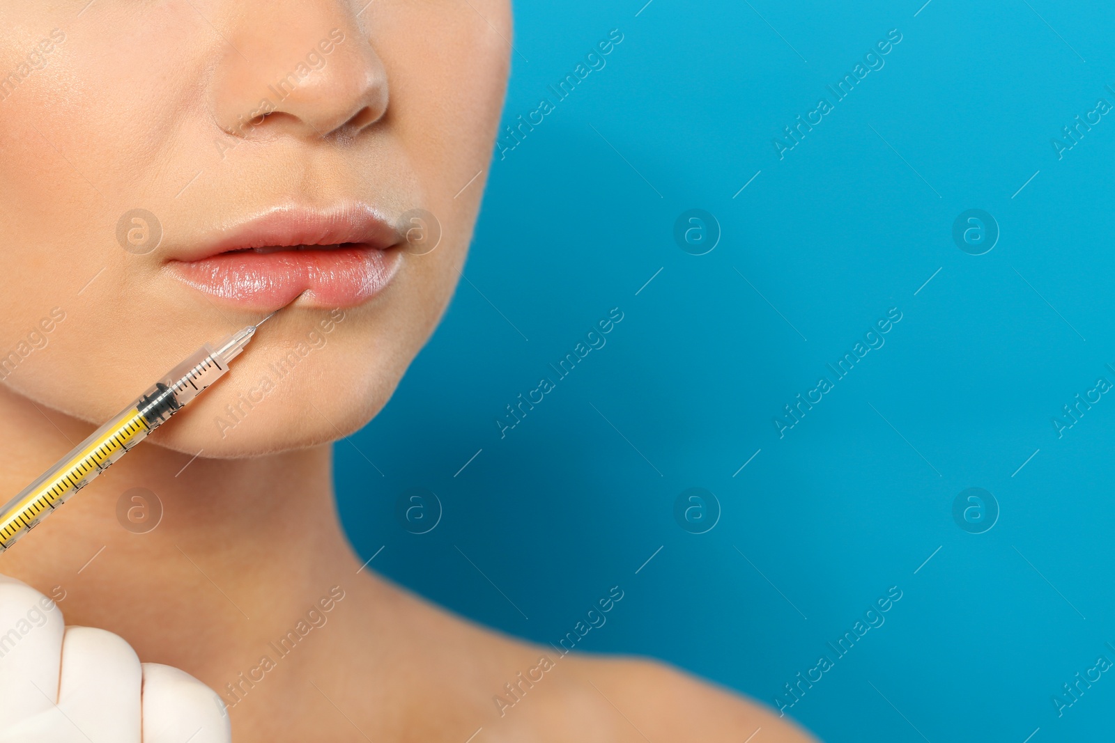 Photo of Young woman getting lips injection on color background, space for text. Cosmetic surgery