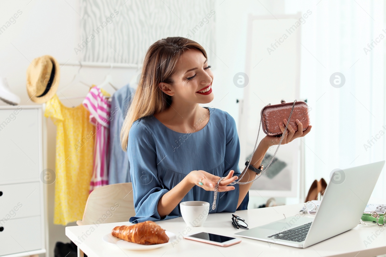 Photo of Portrait of female fashion blogger with clutch and laptop at home. Online broadcast