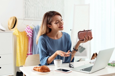 Photo of Portrait of female fashion blogger with clutch and laptop at home. Online broadcast