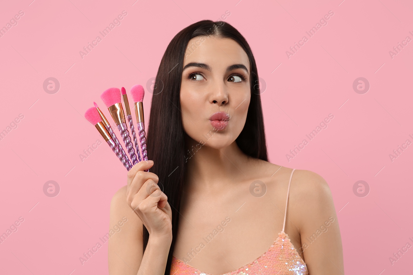 Photo of Beautiful woman with different makeup brushes on pink background