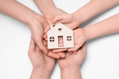 Photo of Home security concept. Family holding house model on white background, top view