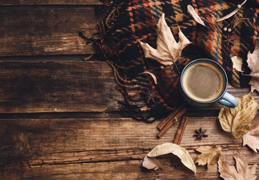 Photo of Flat lay composition with cup of hot drink and autumn leaves on wooden table, space for text. Cozy atmosphere