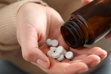 Photo of Woman pouring pills from bottle, closeup view