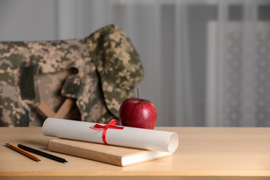 Diploma, apple and stationery on wooden table indoors, space for text. Military education