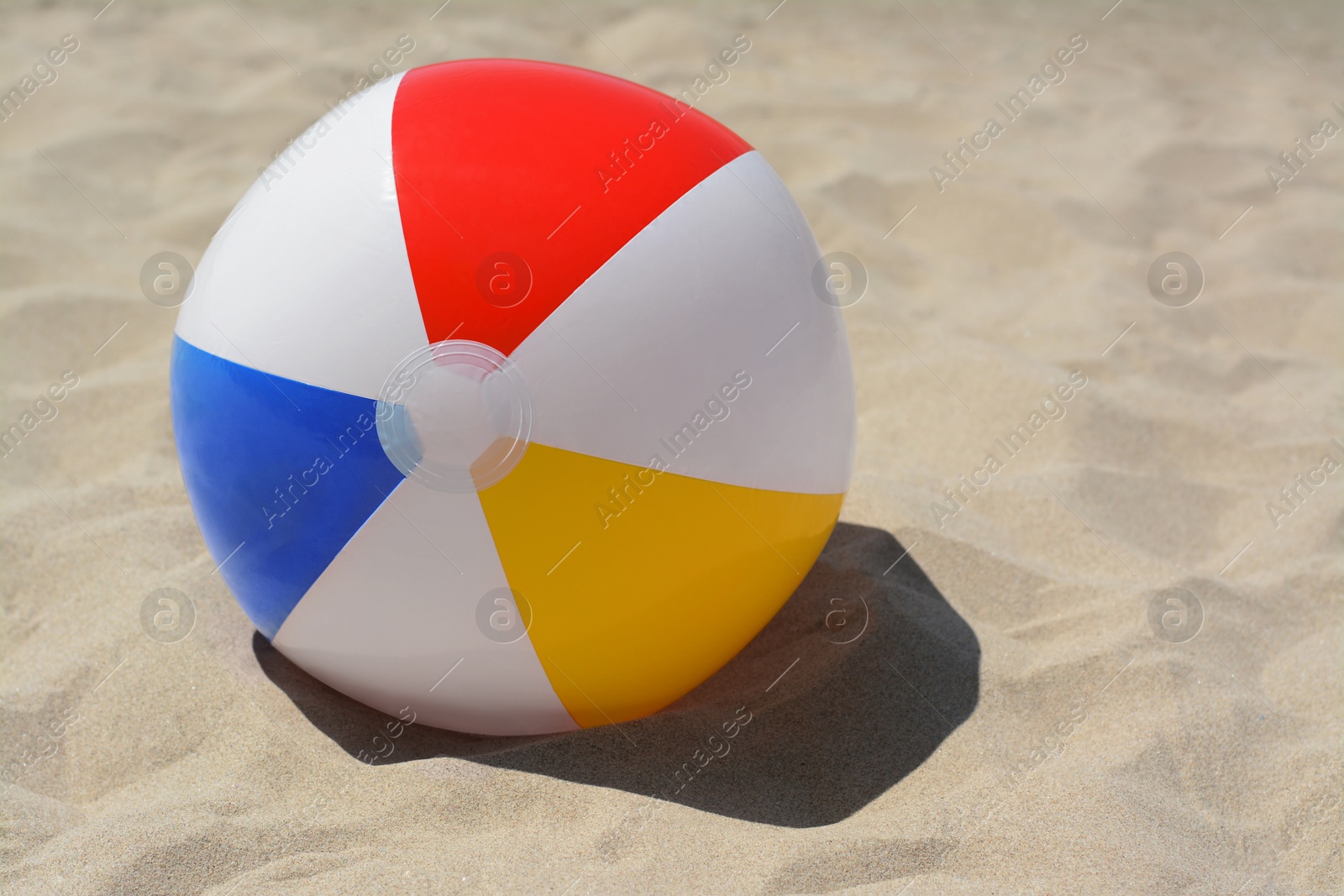 Photo of Colorful beach ball on sand, space for text