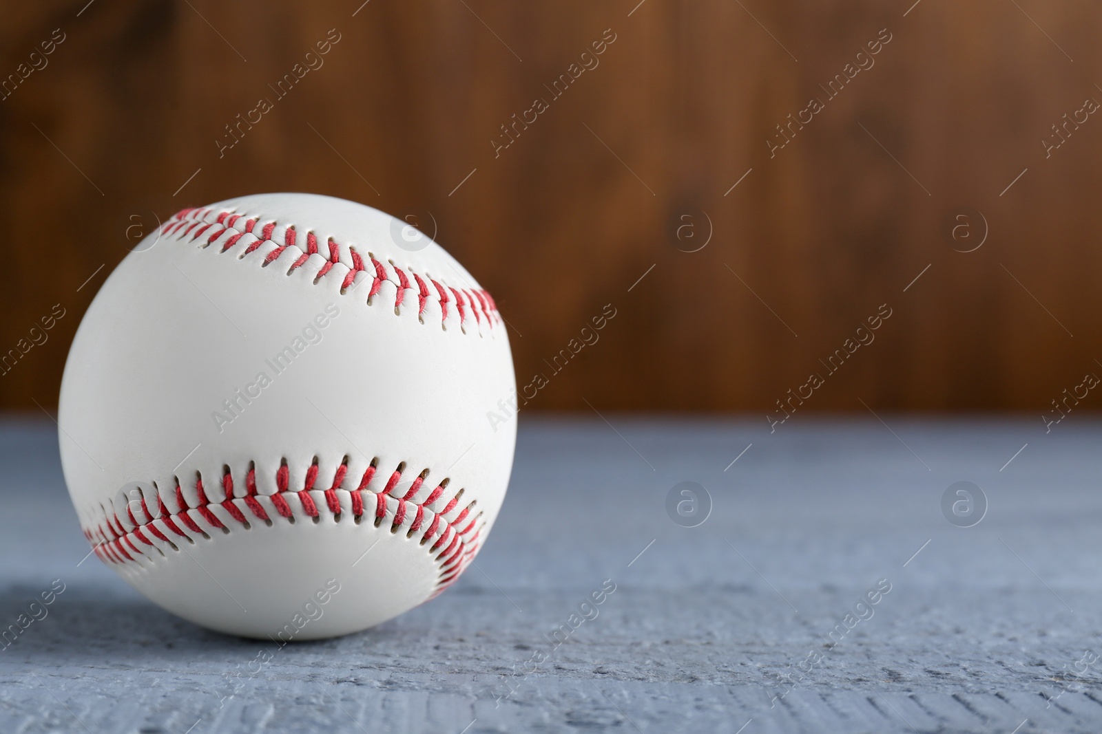 Photo of Baseball ball on grey wooden table, closeup. Space for text
