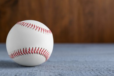 Photo of Baseball ball on grey wooden table, closeup. Space for text
