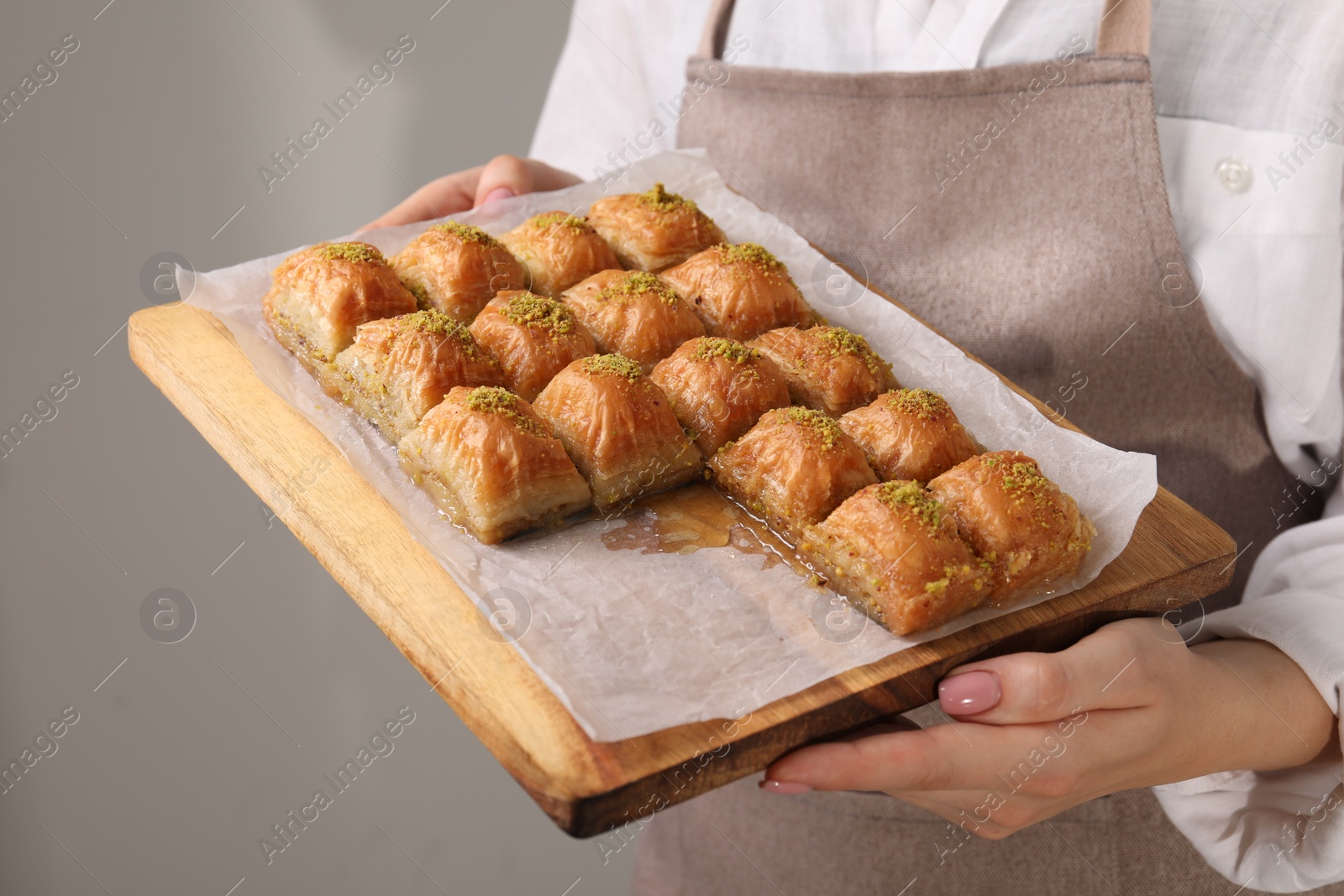 Photo of Woman with delicious sweet baklava on grey background, closeup