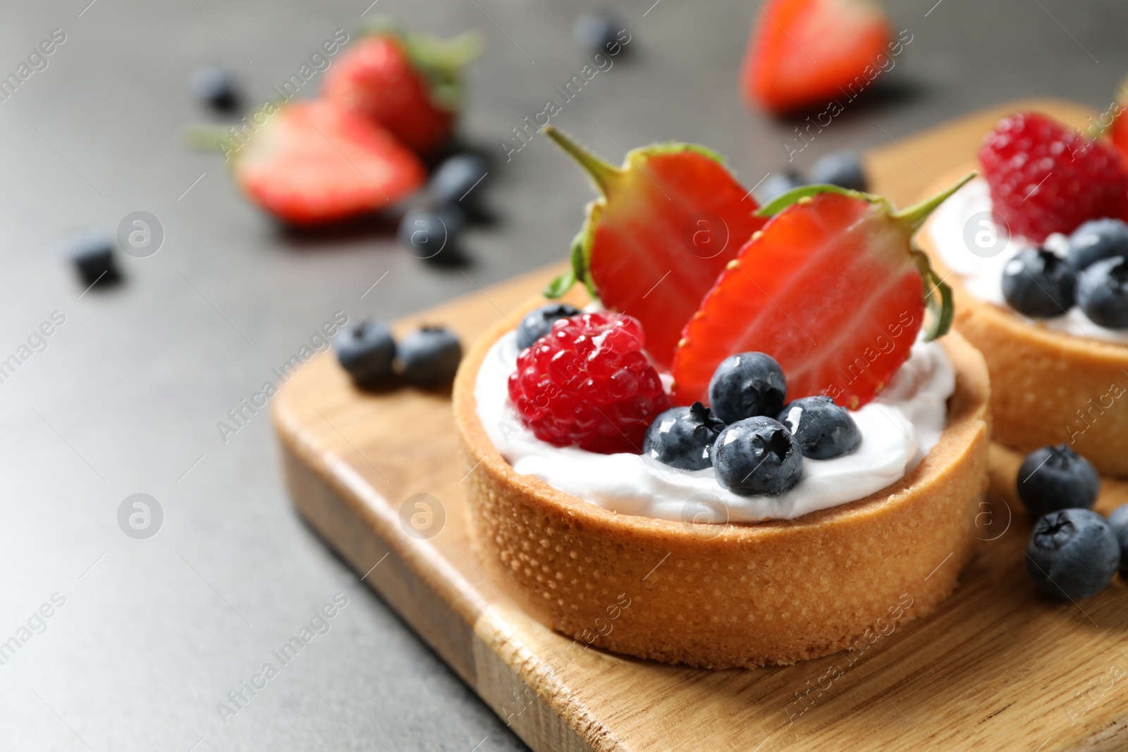 Photo of Delicious sweet pastries with berries on grey table, closeup. Space for text