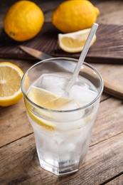 Photo of Soda water with lemon slices and ice cubes on wooden table