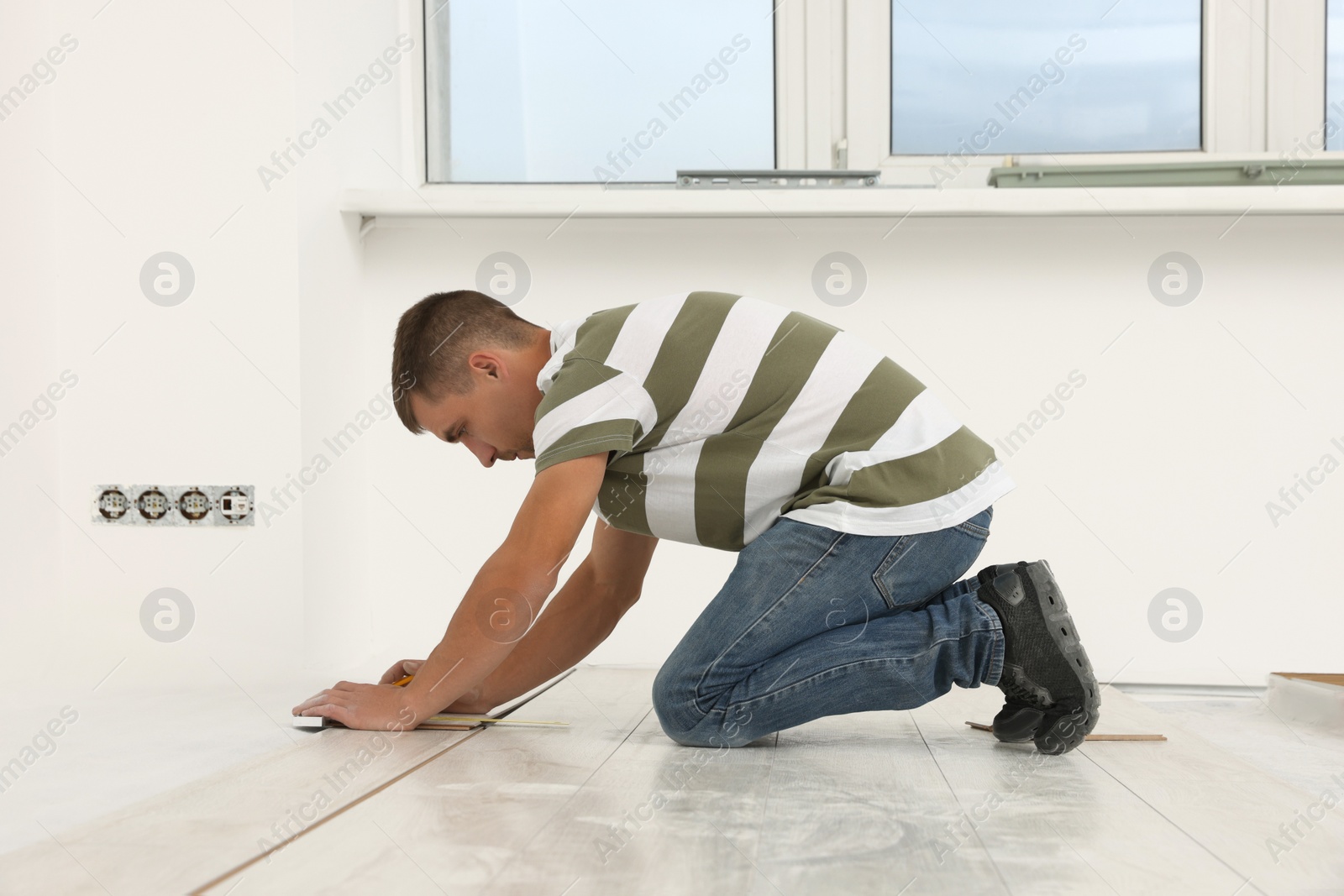 Photo of Professional worker installing new laminate flooring indoors