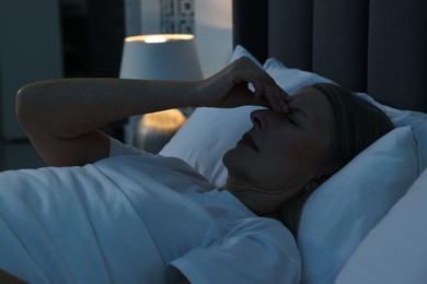 Photo of Woman suffering from headache in bed at night