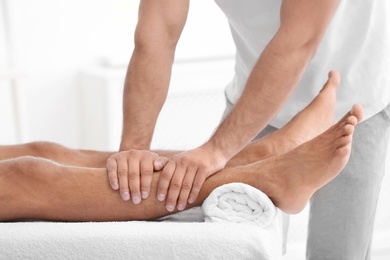 Photo of Young man receiving massage in salon, closeup