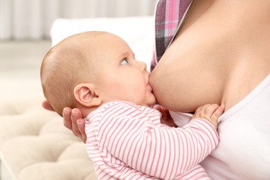 Young woman breastfeeding her little baby at home, closeup