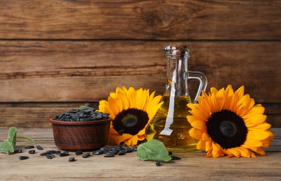 Photo of Sunflower cooking oil, seeds and yellow flowers on wooden table