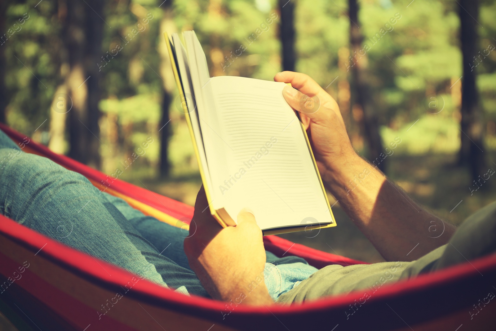 Photo of Man with book relaxing in hammock outdoors on summer day, closeup