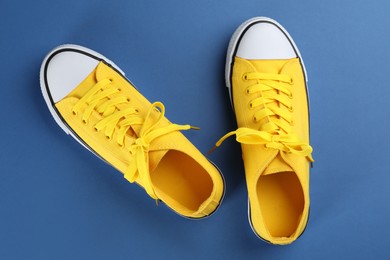 Photo of Pair of trendy sneakers on blue background, flat lay