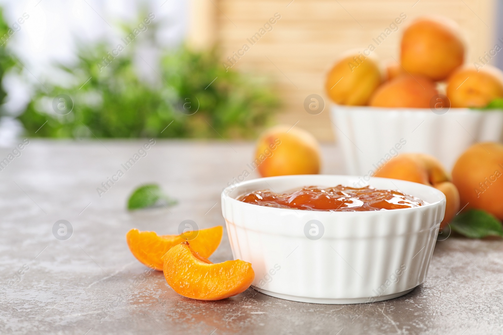 Photo of Bowl with tasty apricot jam on table